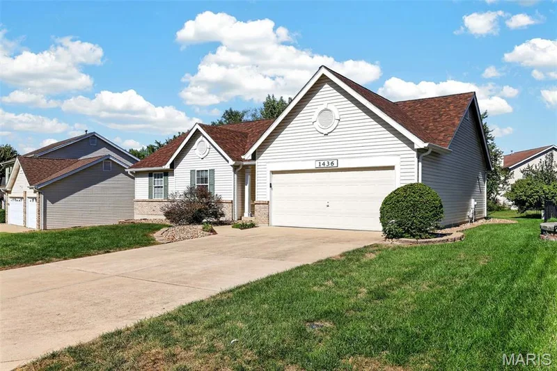 View of the 2 car Garage and Driveway and a view of the side yard — 1436 Snowbird Lane, O'Fallon, MO 63366