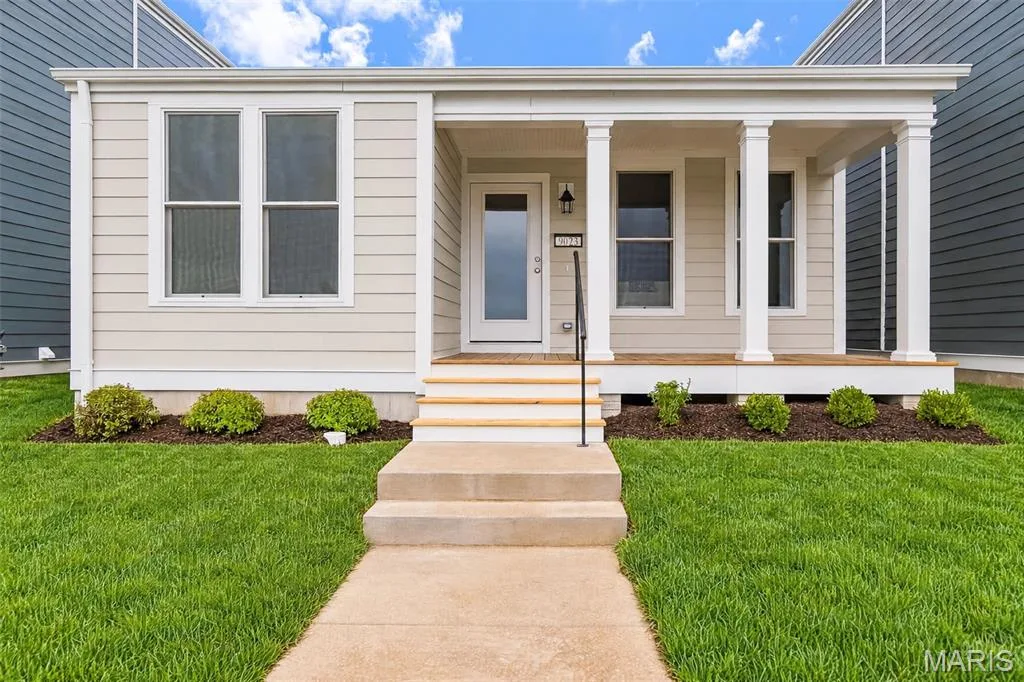 Front exterior featuring a covered porch with white columns, light-colored siding, and a concrete pathway — 9023 Wilkie Station Street, St Charles, MO 63301
