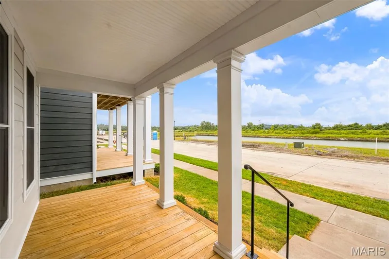 Inviting front porch with wood-finish decking and white structural columns — 9023 Wilkie Station Street, St Charles, MO 63301