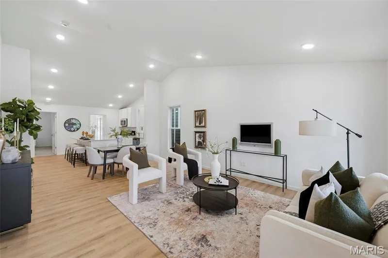 Open-concept living area featuring LVP flooring, recessed lighting, and vaulted ceilings — 9023 Wilkie Station Street, St Charles, MO 63301