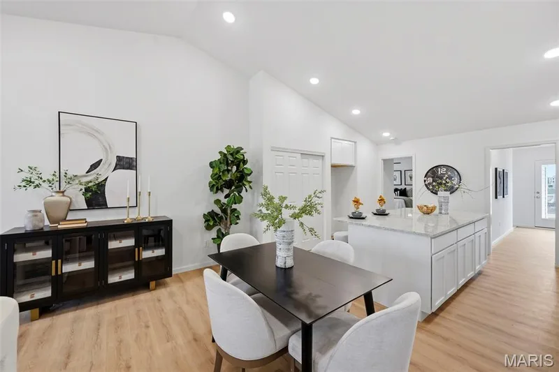 Vaulted ceilings, LVP flooring, recessed lighting, white cabinetry, and a kitchen island with granite countertop — 9023 Wilkie Station Street, St Charles, MO 63301