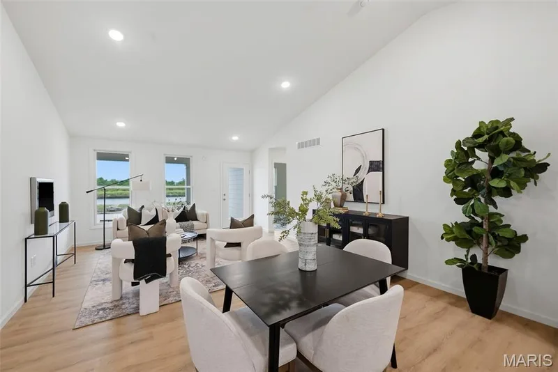 Vaulted ceiling, recessed lighting, LVP flooring, multiple windows, and a glass-paneled exterior door — 9023 Wilkie Station Street, St Charles, MO 63301