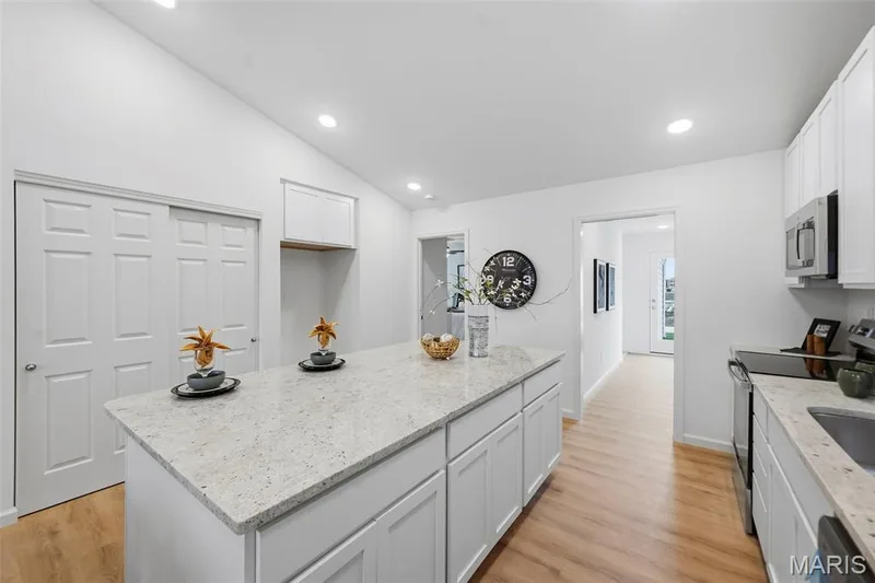 Kitchen featuring a granite-topped island, white cabinetry, stainless steel appliances — 9023 Wilkie Station Street, St Charles, MO 63301