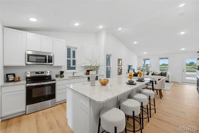Kitchen with white cabinetry, stainless steel appliances, and a central island with granite countertop seating — 9023 Wilkie Station Street, St Charles, MO 63301
