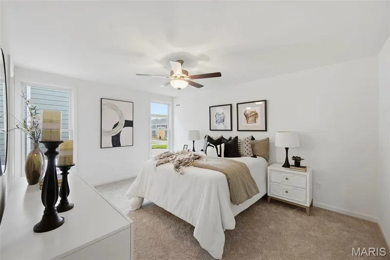 White walls, light-colored carpet, ceiling fan with light fixture, and multiple windows with white trim — 9023 Wilkie Station Street, St Charles, MO 63301