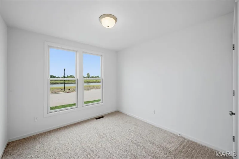Bright room with two large windows, white walls, and neutral carpet flooring — 9023 Wilkie Station Street, St Charles, MO 63301