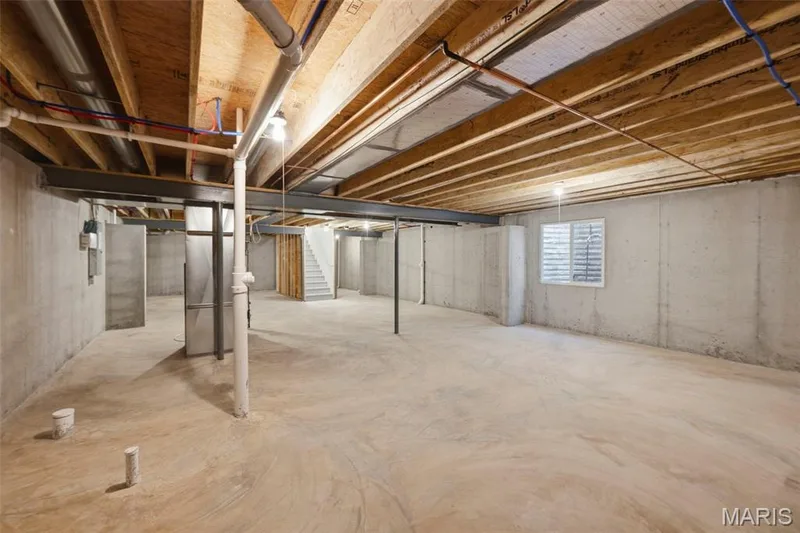 Unfinished concrete basement with exposed wood joists, steel beams, and a window with blinds — 9023 Wilkie Station Street, St Charles, MO 63301