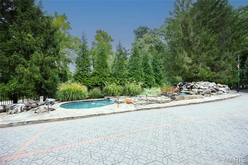 Paver driveway with an intricate pattern, surrounded by mature trees and landscaping — 76 River Valley Drive, Chesterfield, MO 63017