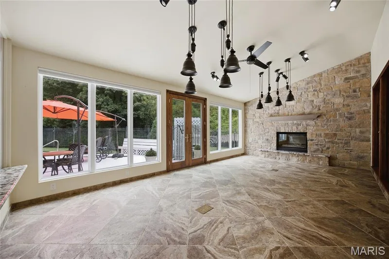 Heated flooring, full-height stone accent wall with fireplace, ceiling fan, and French doors to outdoor patio — 76 River Valley Drive, Chesterfield, MO 63017