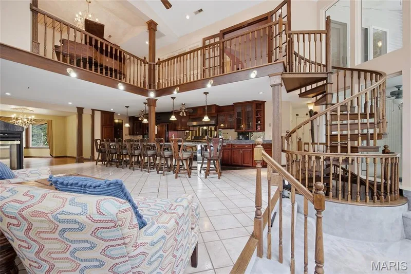 High ceilings with recessed lighting, tile flooring, a detailed spiral staircase, and an open-concept kitchen with wood cabinetry — 76 River Valley Drive, Chesterfield, MO 63017