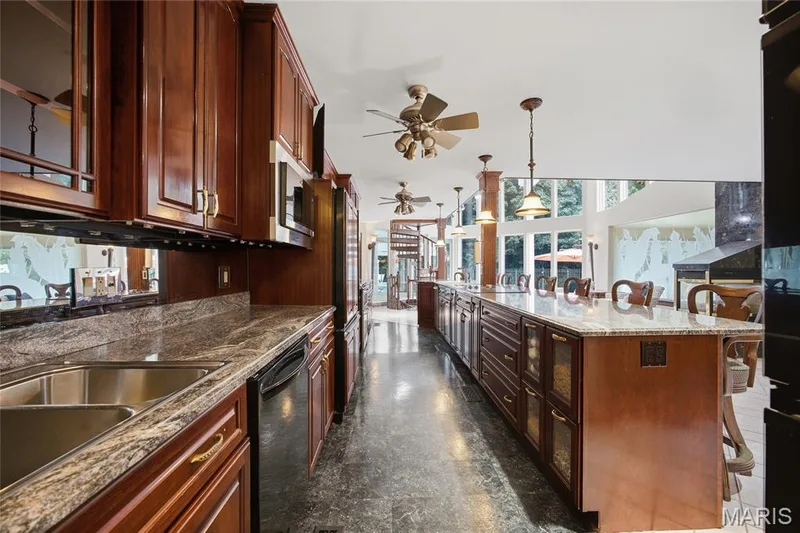 Expansive kitchen featuring wood cabinetry, integrated stainless steel appliances, a large island with a stone countertop, and high ceilings with recessed lighting — 76 River Valley Drive, Chesterfield, MO 63017