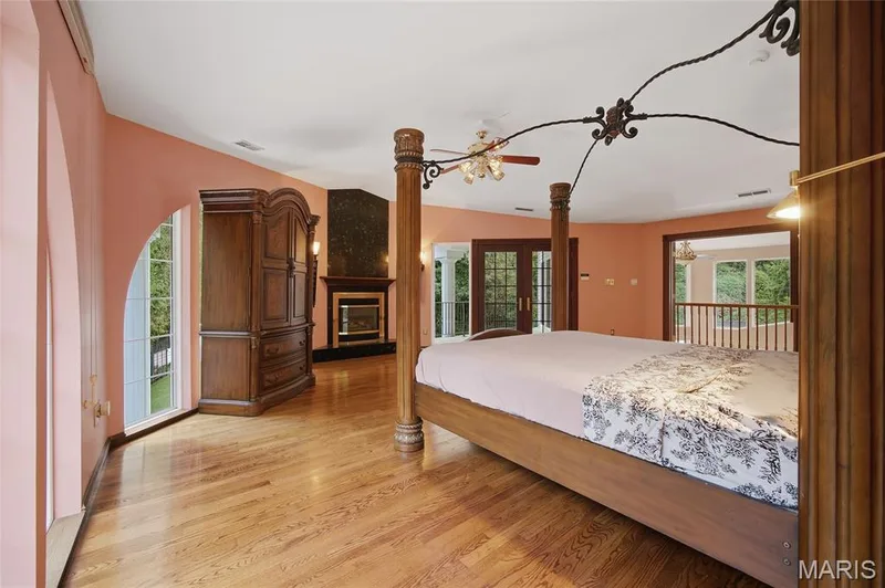 Hardwood flooring, arched window, fireplace with dark stone surround, double French doors, ceiling fan with light fixture — 76 River Valley Drive, Chesterfield, MO 63017