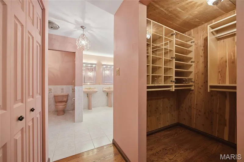 Hallway with wood-finish flooring, leading to a bathroom with dual pedestal sinks and a cedar-lined closet featuring built-in shelving — 76 River Valley Drive, Chesterfield, MO 63017