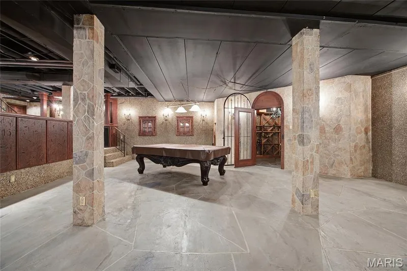 Stone-clad columns and walls, natural stone flooring, arched doorway with ironwork, built-in wine storage, and recessed lighting — 76 River Valley Drive, Chesterfield, MO 63017