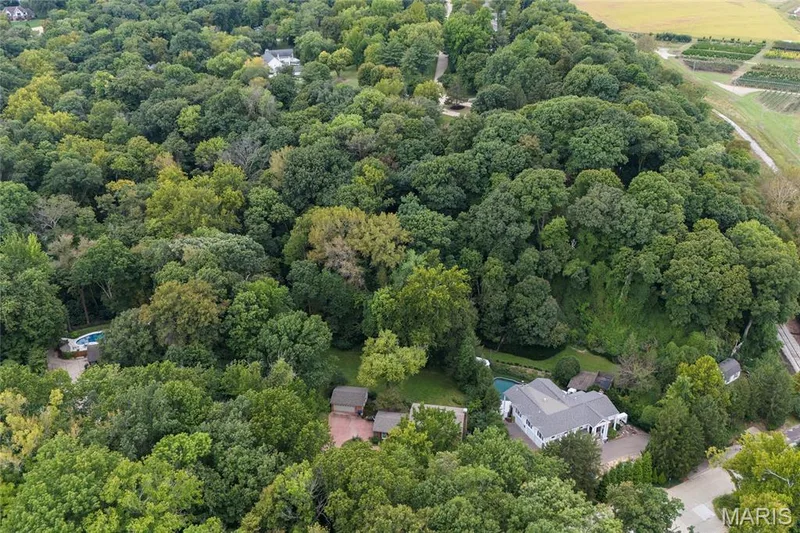 Extensive tree canopy surrounds the property, featuring a main residence with a gray roof, a swimming pool, and barn — 76 River Valley Drive, Chesterfield, MO 63017