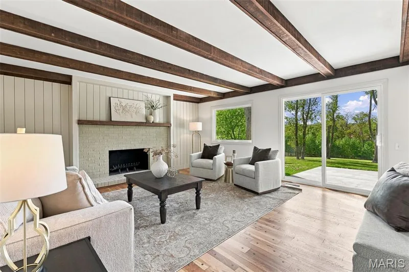 Exposed wood ceiling beams, a brick fireplace with wood mantel, renewed hardwood flooring, and a new sliding glass door leading to an outdoor patio and picturesque back yard — 621 Claymont Estates Drive, Chesterfield, MO 63017