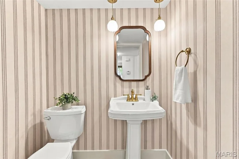 Main Level Half Bath with Pedestal sink featuring brass-finish fixtures, wall-mounted mirror, and striped wall covering and checkered flooring. — 621 Claymont Estates Drive, Chesterfield, MO 63017
