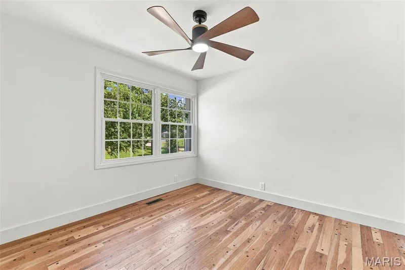 Bedroom 3 Hardwood flooring, white walls, new double-paned window, and a ceiling fan with light fixture — 621 Claymont Estates Drive, Chesterfield, MO 63017