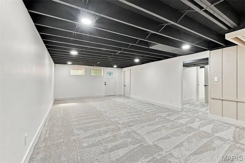 Spacious room featuring patterned carpeting, white walls, and a dark exposed ceiling — 621 Claymont Estates Drive, Chesterfield, MO 63017