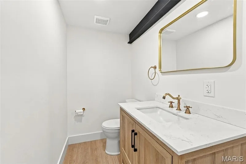 Lower level bath... Built-in vanity with light wood-finish cabinetry, white countertop, and gold-finish fixtures — 621 Claymont Estates Drive, Chesterfield, MO 63017