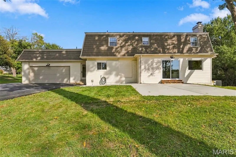 Gambrel roofline with dormer windows, attached two-car garage, rear patio, and sliding glass doors — 621 Claymont Estates Drive, Chesterfield, MO 63017