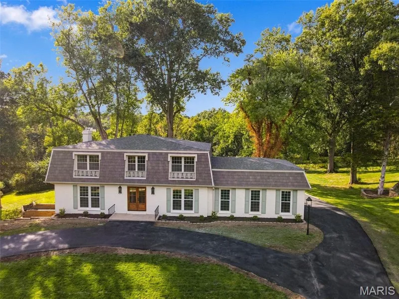 Dormered gambrel roofline with white exterior, light green shutters, and a double wood-finish entry door — 621 Claymont Estates Drive, Chesterfield, MO 63017