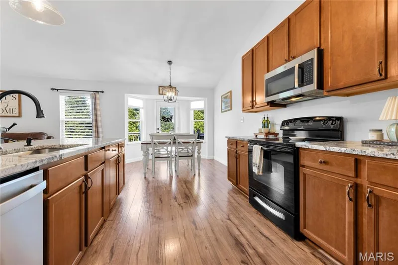 Wood-finish flooring throughout, complemented by wood cabinetry and stone countertops — 5507 Dressel Drive, Cottleville, MO 63304