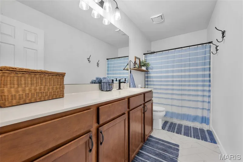 Wood-finish cabinetry with dark hardware, a light-toned countertop, and a built-in sink with a matte black faucet — 5507 Dressel Drive, Cottleville, MO 63304