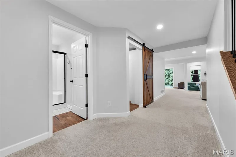 White six-panel interior door, wood-finish flooring, wood barn door with black hardware, recessed lighting, and light-toned carpeting — 5507 Dressel Drive, Cottleville, MO 63304