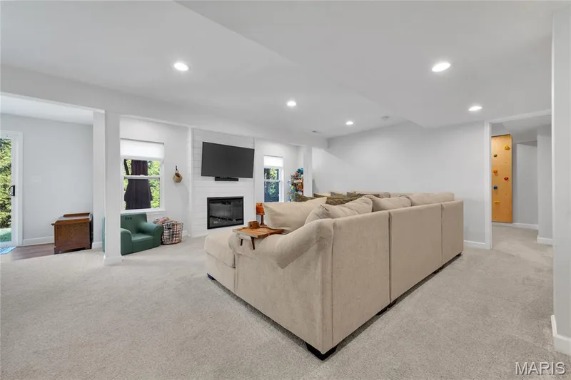Recessed lighting illuminates the carpeted living area, featuring a fireplace with a shiplap surround — 5507 Dressel Drive, Cottleville, MO 63304