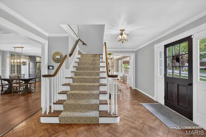 Herringbone flooring highlights the turned staircase in the center foyer. — 1165 Templeton Place, Chesterfield, MO 63017