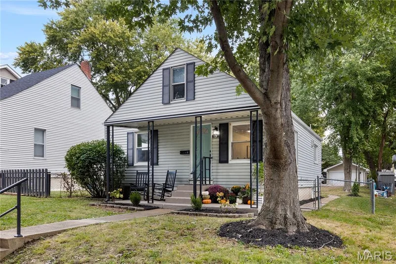 Exterior featuring light-colored siding, a covered front porch, and dark-framed windows with shutters — 924 N Benton Avenue, St Charles, MO 63301