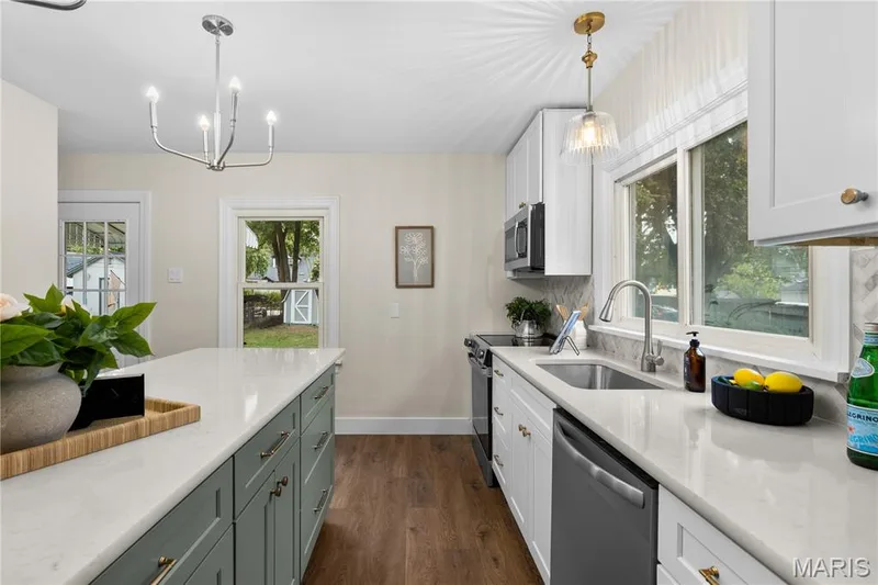 Kitchen featuring a center island with custom cabinetry, quartz countertops, stainless steel appliances, a tile backsplash, and wood-finish flooring — 924 N Benton Avenue, St Charles, MO 63301