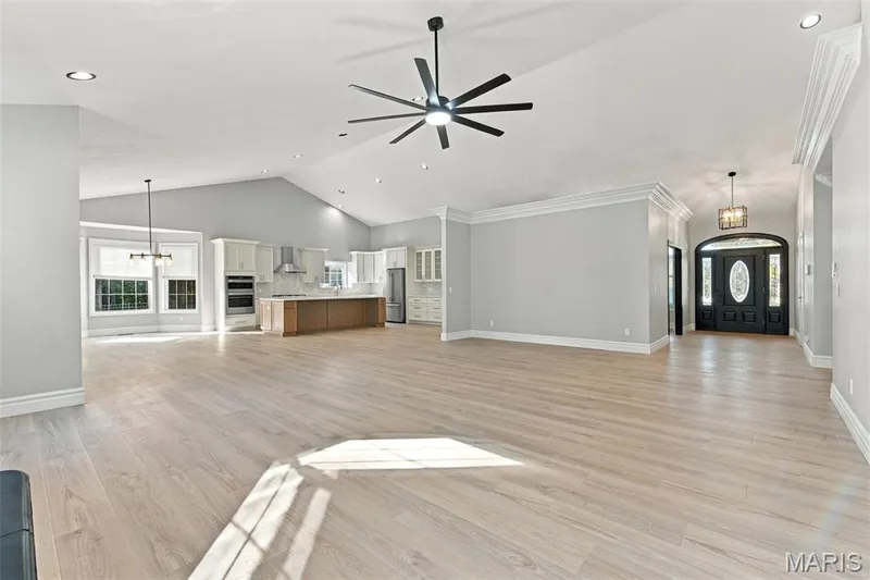 Vaulted ceilings with recessed lighting, luxury vinyl plank flooring, a contemporary ceiling fan, and a kitchen featuring stainless steel appliances and an island — 1580 Madre Drive, Foristell, MO 63348