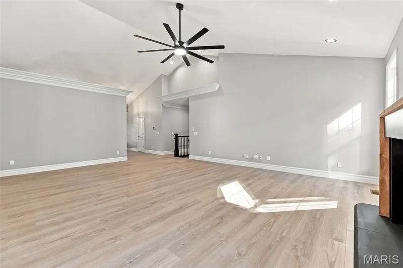 Vaulted ceilings with a black ceiling fan, luxury vinyl plank flooring, white trim, and a fireplace with a wood mantel — 1580 Madre Drive, Foristell, MO 63348