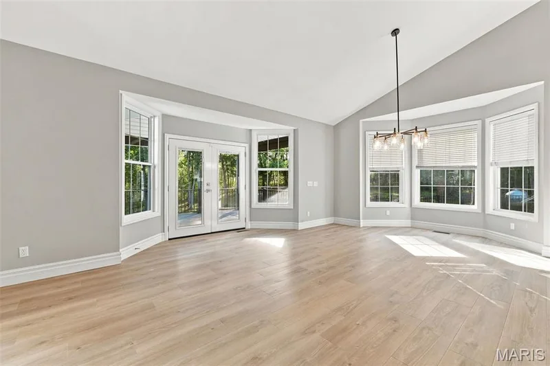 Vaulted ceiling, bay windows, patio access, luxury vinyl plank flooring, and a modern chandelier — 1580 Madre Drive, Foristell, MO 63348