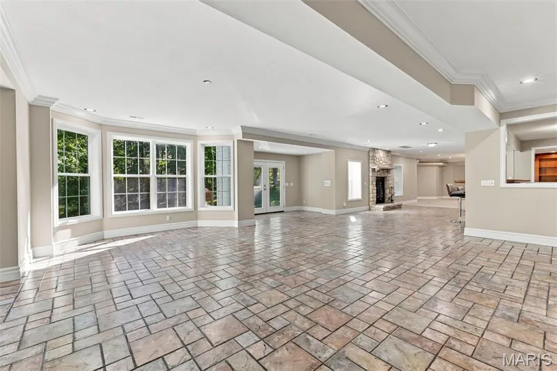 Expansive open-concept living area featuring a bay window, French doors, stone fireplace, recessed lighting, and patterned tile flooring — 1580 Madre Drive, Foristell, MO 63348