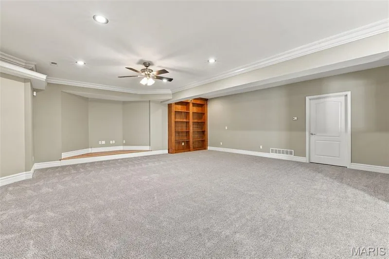 Expansive carpeted room featuring recessed lighting, a ceiling fan, crown molding, and built-in wood shelving — 1580 Madre Drive, Foristell, MO 63348