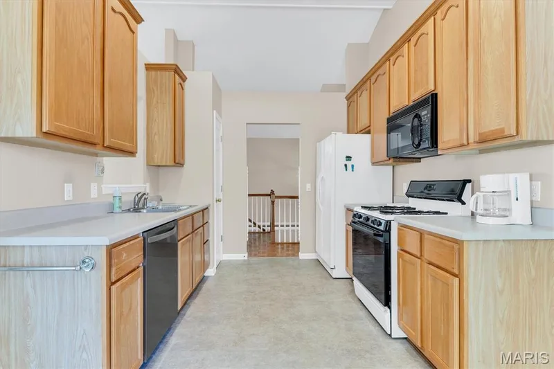 Galley kitchen between entry foyer & breakfast room includes gas stove top/oven, built-in microwave & refrigerator. — 18 Country Bluff Court, St Charles, MO 63301