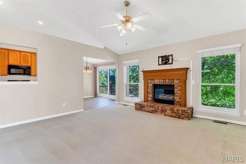 Left: pier-through opening to kitchen. Center: breakfast room/deck. Right living room brick-surround fireplace. — 18 Country Bluff Court, St Charles, MO 63301