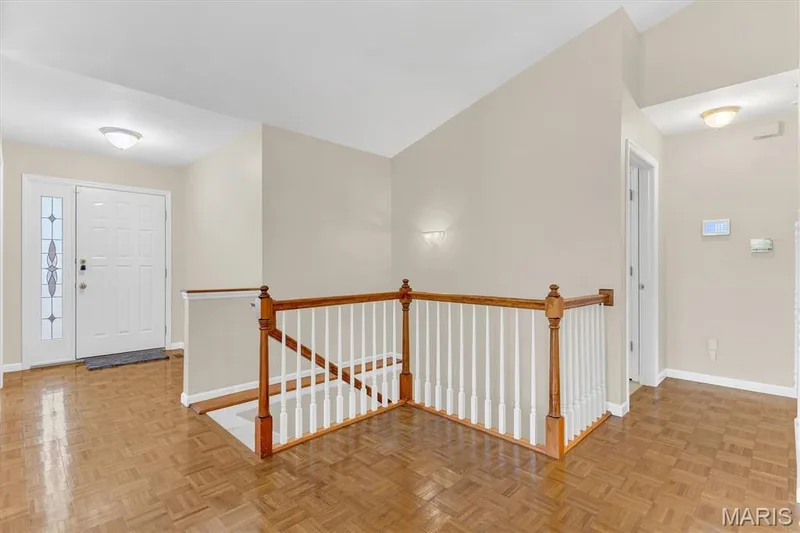 Parquet entry foyer staircase to lower level (center), stain glass front door (left) and main floor laundry (right). — 18 Country Bluff Court, St Charles, MO 63301