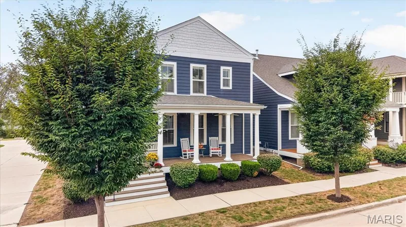 Two-story residence featuring blue siding with white trim, a covered front porch with white columns, and a gabled roof — 3708 Broad Street, St Charles, MO 63301