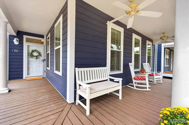 Covered front porch featuring blue horizontal siding, white trim, wood-finish decking, and recessed lighting — 3708 Broad Street, St Charles, MO 63301