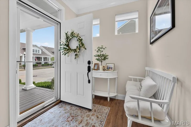 Entryway featuring wood-finish flooring, a white paneled entry door with black hardware, and two upper transom windows — 3708 Broad Street, St Charles, MO 63301