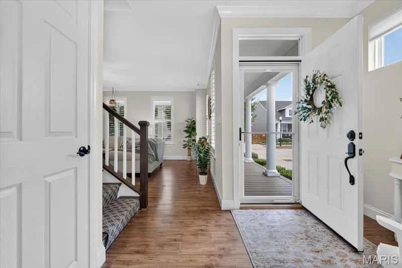 Entryway featuring wood-finish flooring, white paneled doors, and a staircase with a patterned runner — 3708 Broad Street, St Charles, MO 63301
