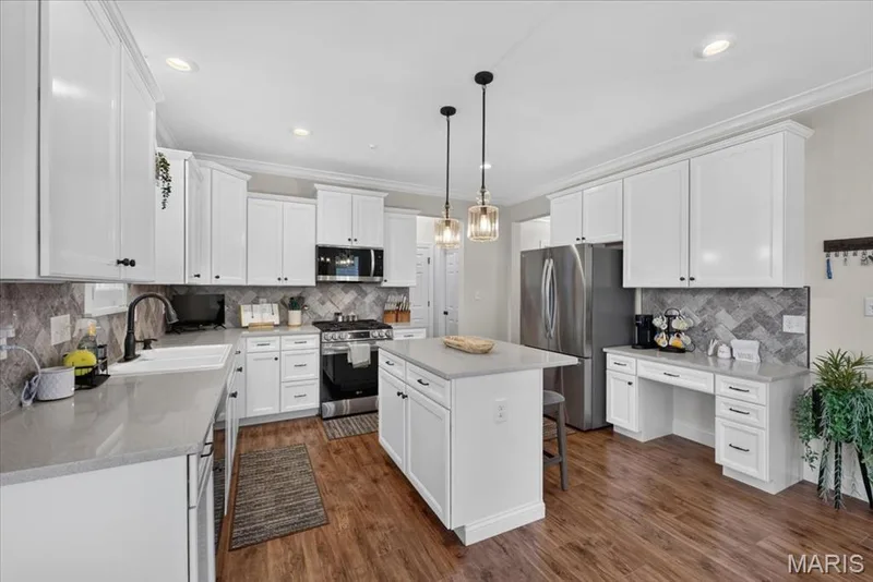 White cabinetry, stainless steel appliances, central island, wood-finish flooring, and a patterned backsplash — 3708 Broad Street, St Charles, MO 63301