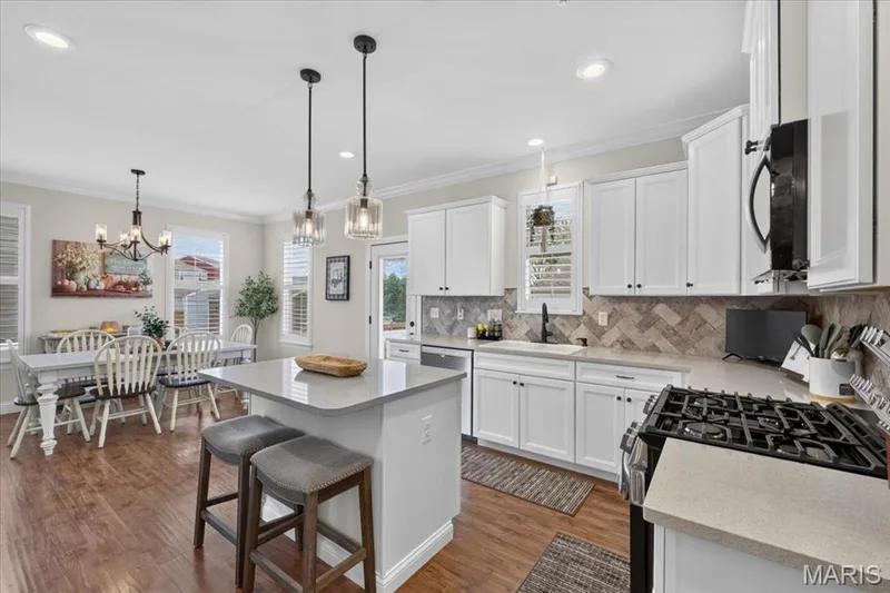 White cabinetry, light-toned countertops, wood-finish flooring, herringbone tile backsplash, and recessed lighting — 3708 Broad Street, St Charles, MO 63301