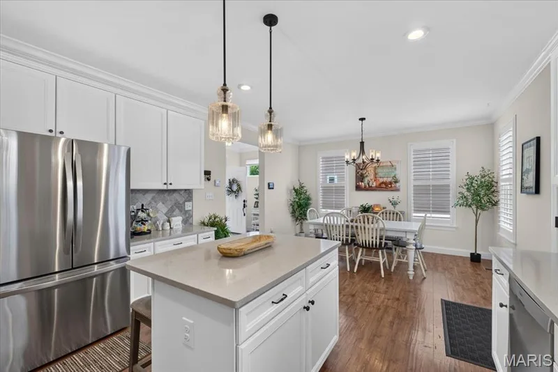 Gourmet kitchen with stainless steel appliances, white cabinetry, a central island with countertop, and wood-finish flooring — 3708 Broad Street, St Charles, MO 63301