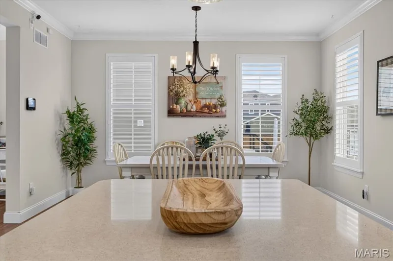 Dining area with multiple windows featuring plantation shutters, crown molding, and a chandelier — 3708 Broad Street, St Charles, MO 63301