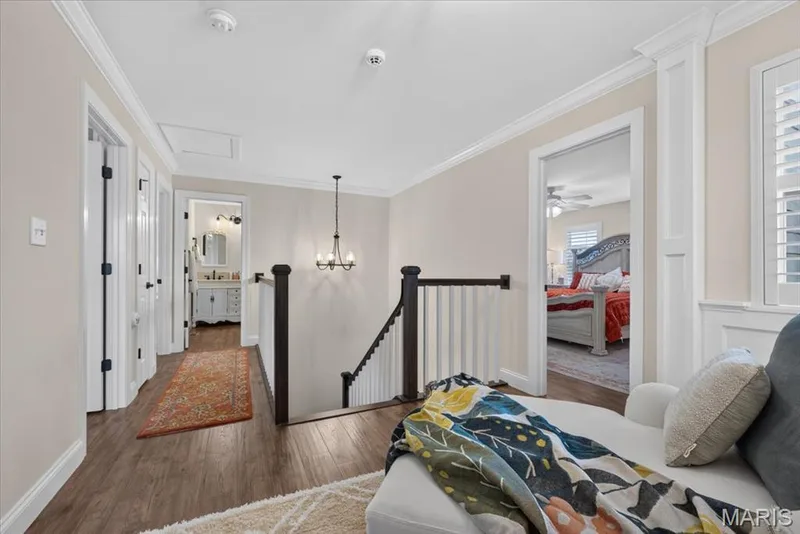 Wood-finish flooring throughout, white trim and crown molding, and a dark wood and white spindle staircase — 3708 Broad Street, St Charles, MO 63301